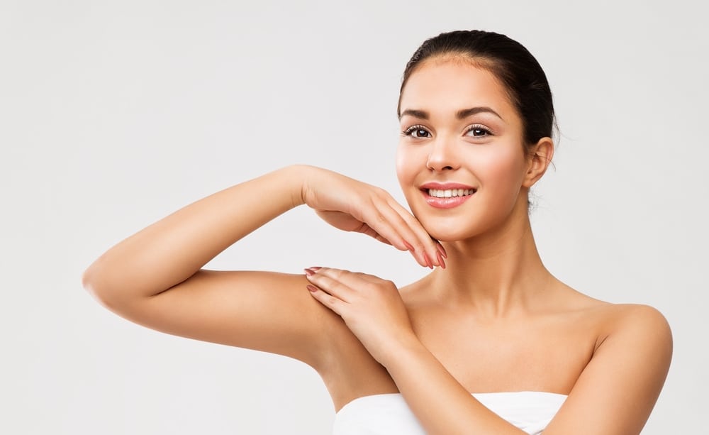 Pretty young woman lifting her arm to show her smooth skin after laser hair removal treatment.