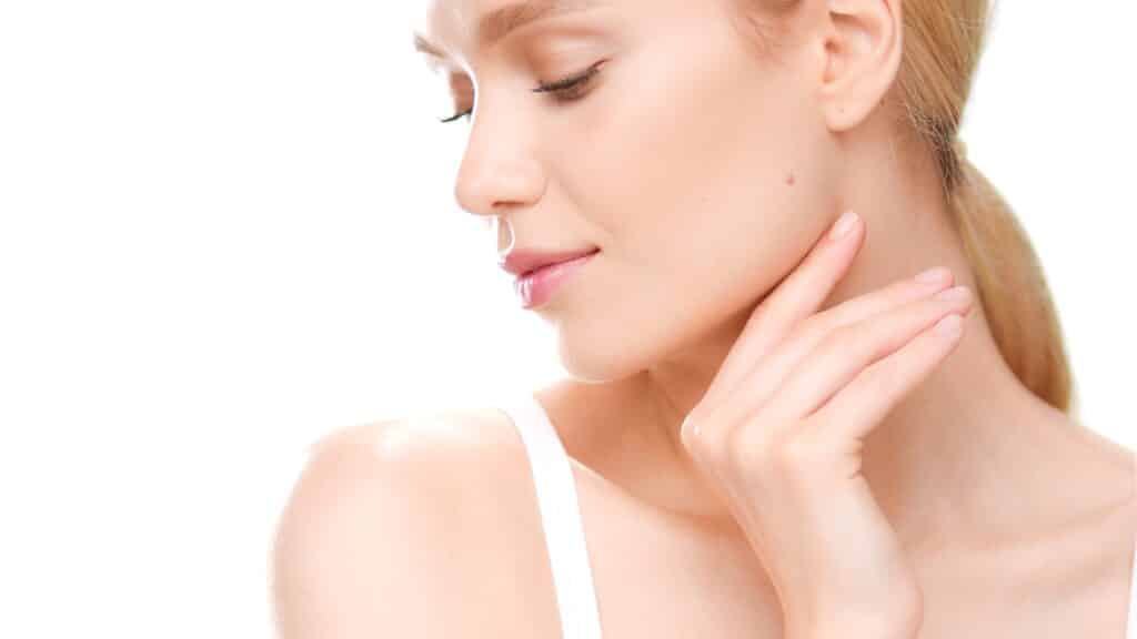 Side profile of a beautiful woman touching her sharp jawline after getting Kybella injections.